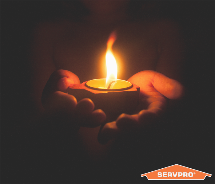A hand holding a lid up candle, SERVPRO logo